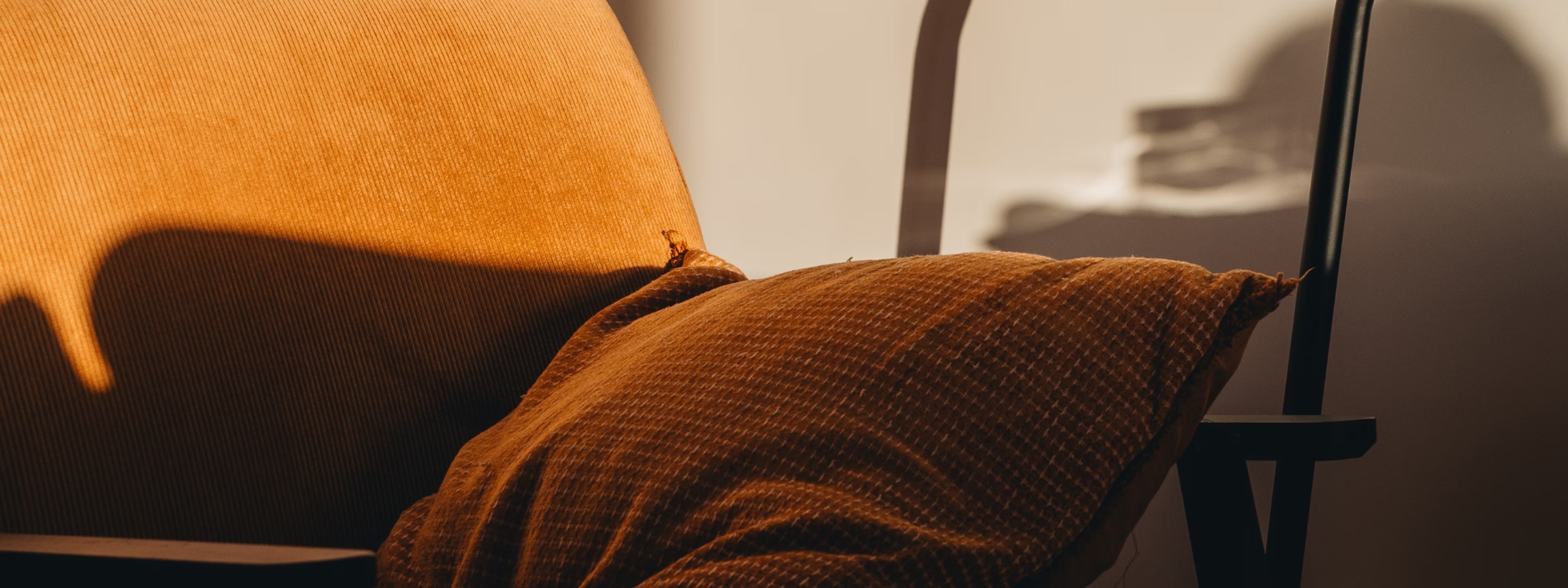 Warm orange textured cushion draped over modern chair with shadow