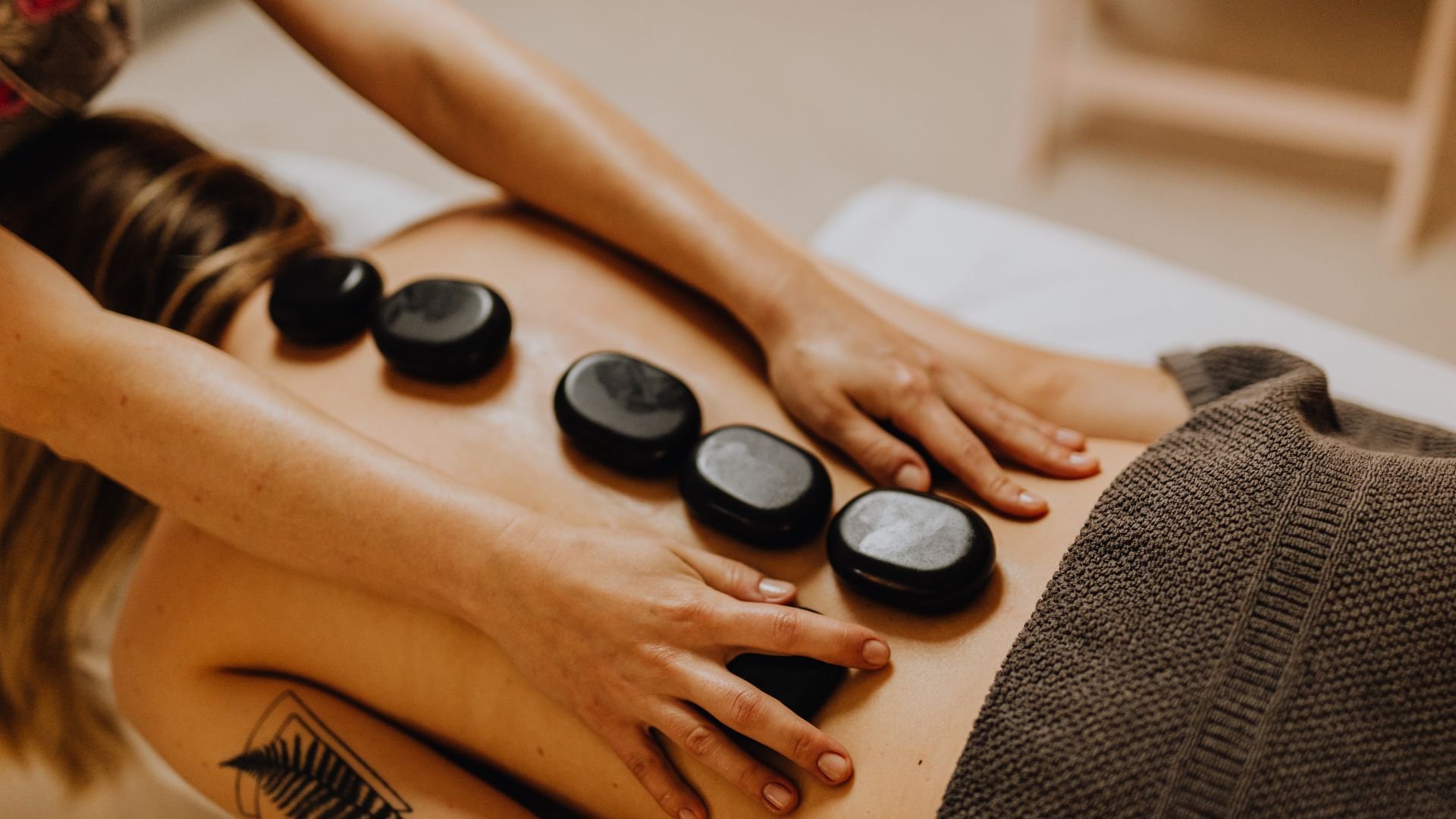 Hot stone massage therapy with smooth black stones on back