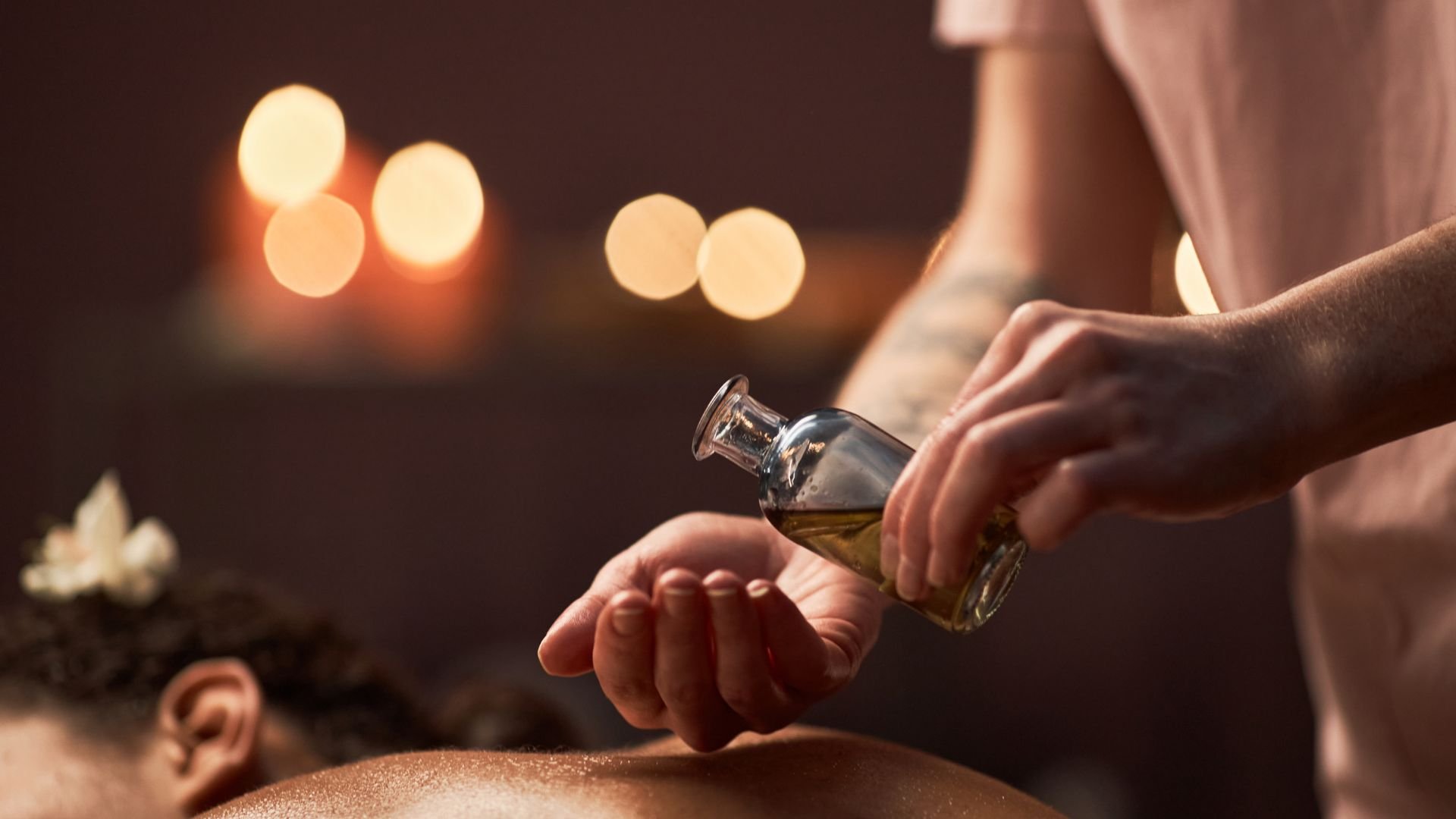 Massage therapist applying oil during relaxing spa treatment with candles