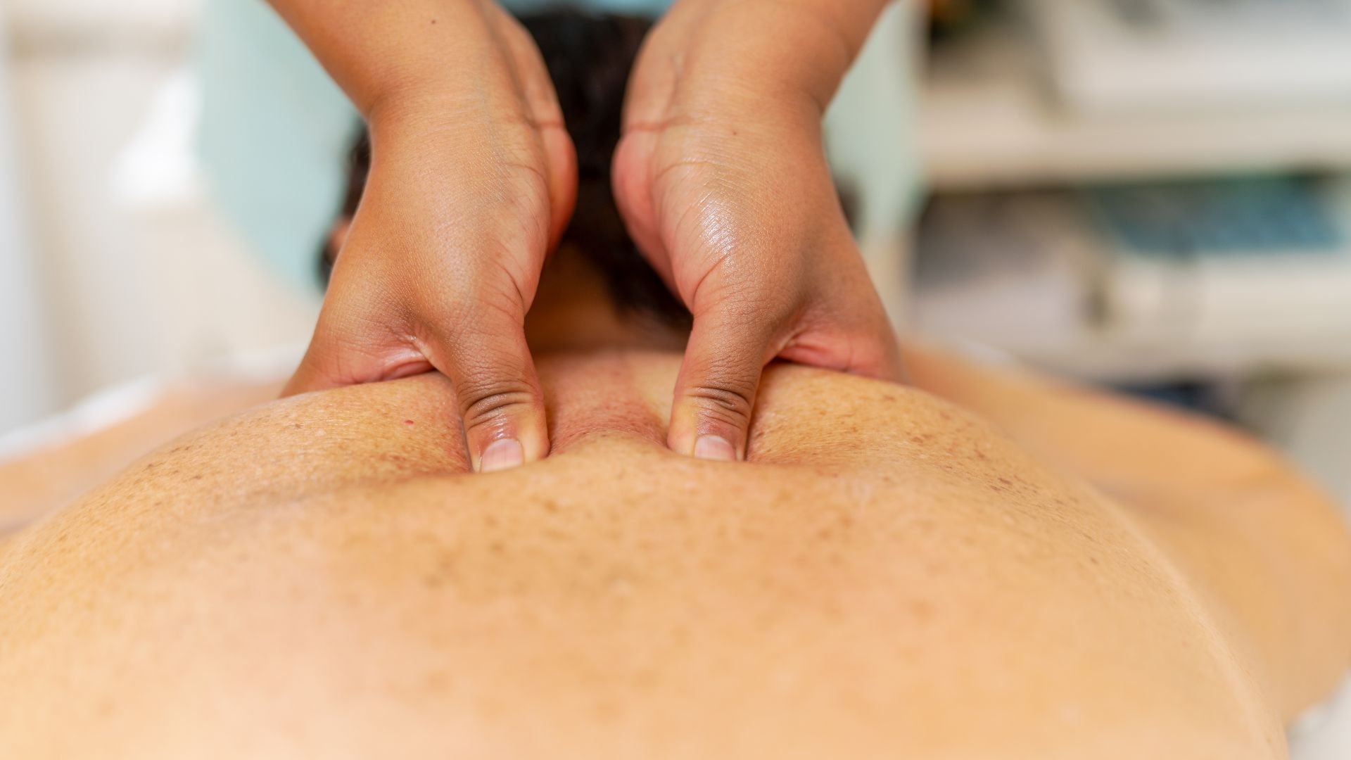 Massage therapist's hands applying pressure on client's back during treatment