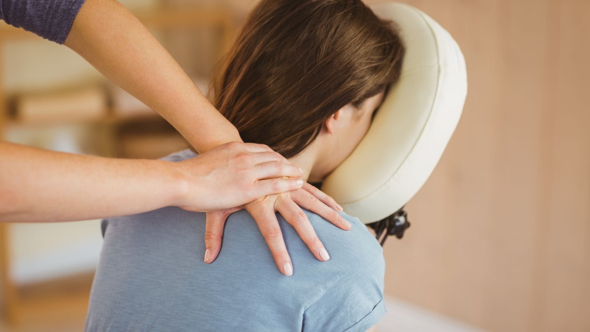 Massage therapist provides back massage to patient on padded treatment chair