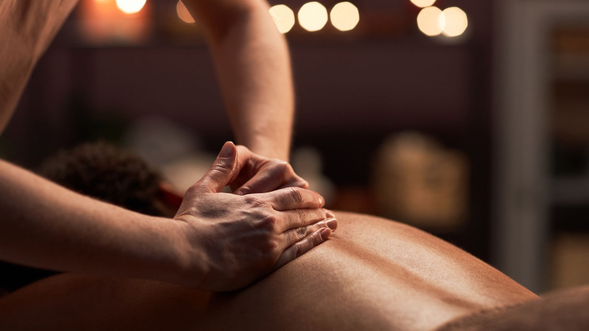 Hands performing massage therapy with soft lighting in background