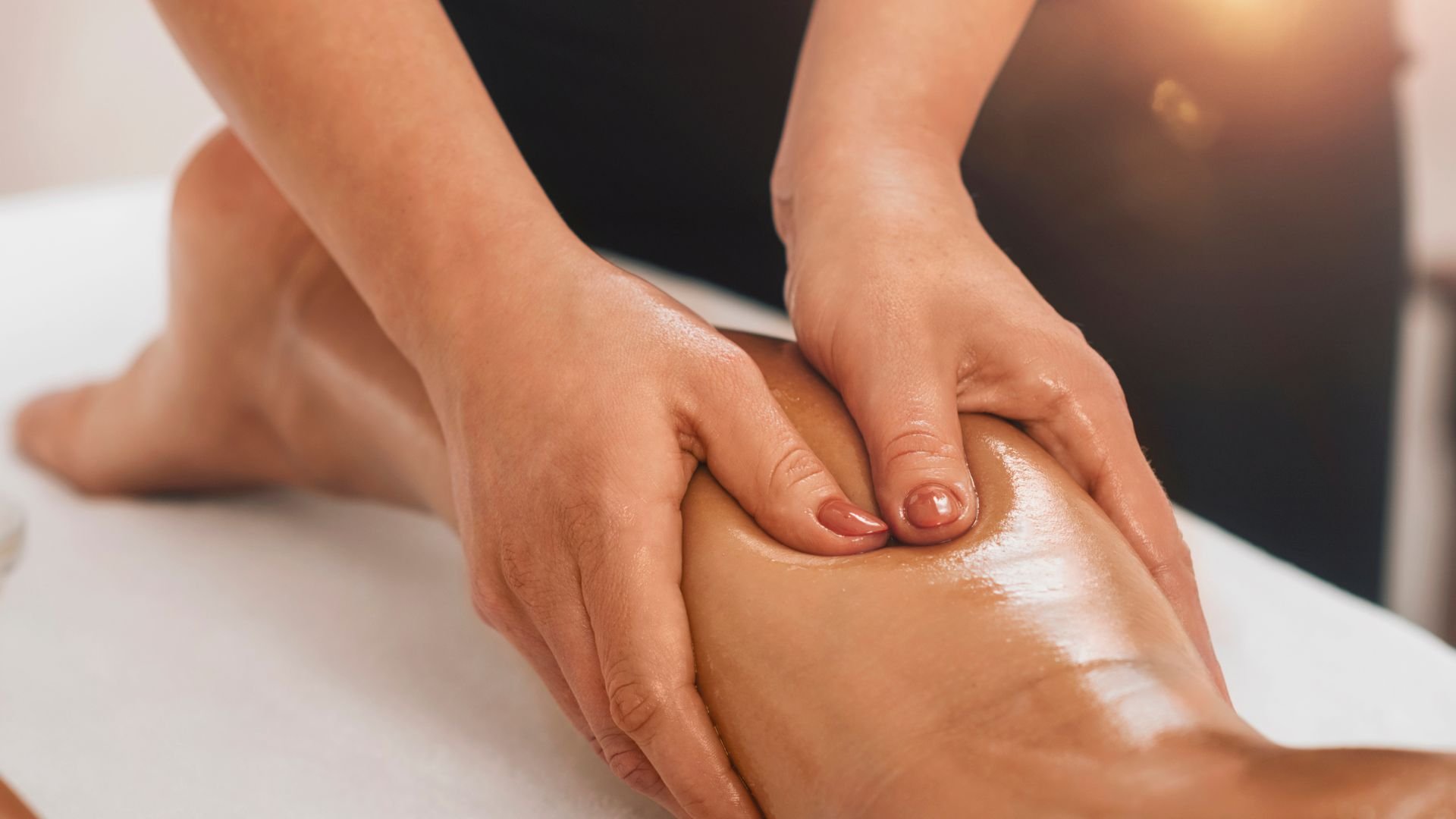 Hands massaging oiled leg during professional therapeutic massage treatment