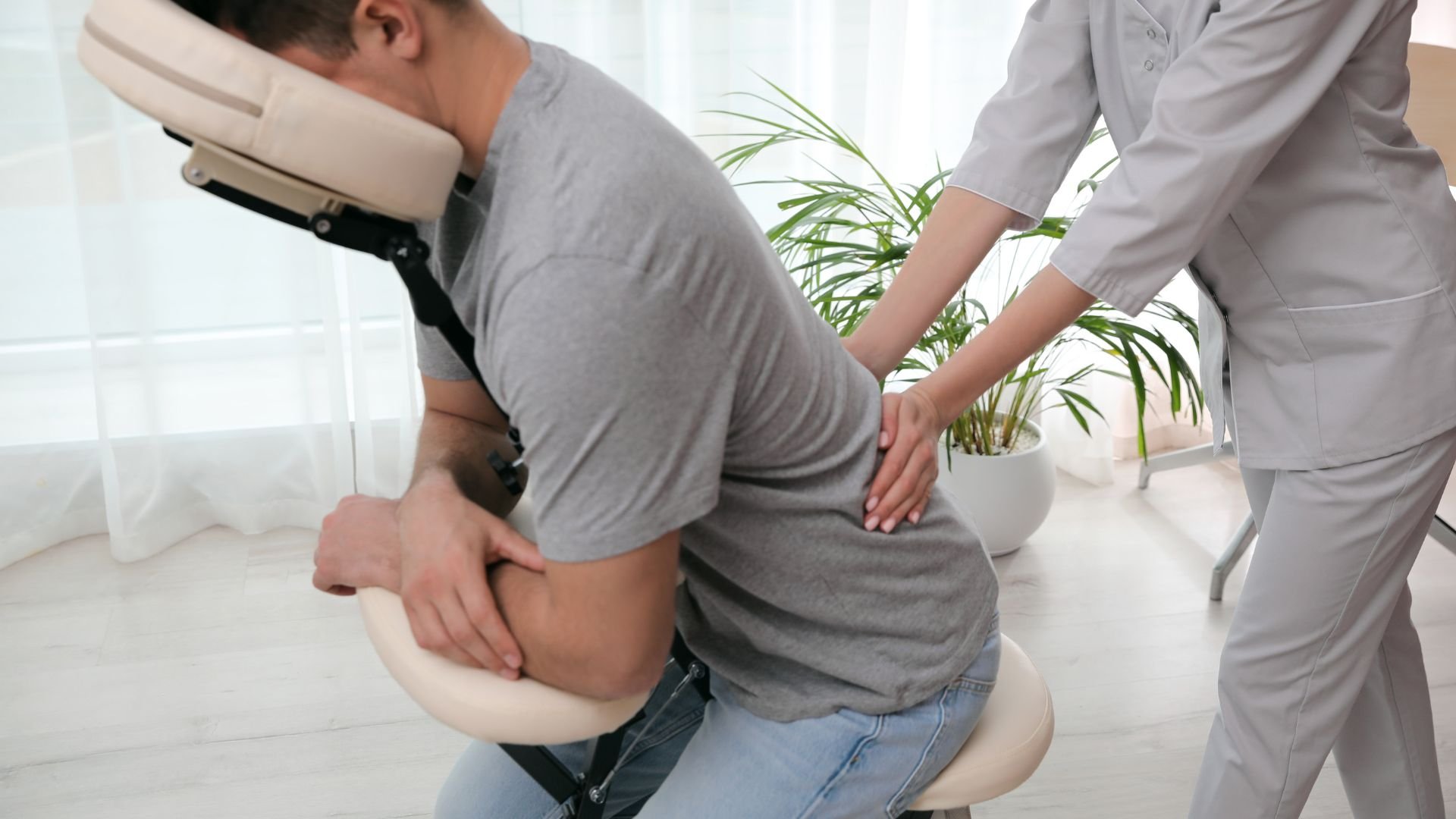 Massage therapist treating patient on ergonomic chair in clinical setting